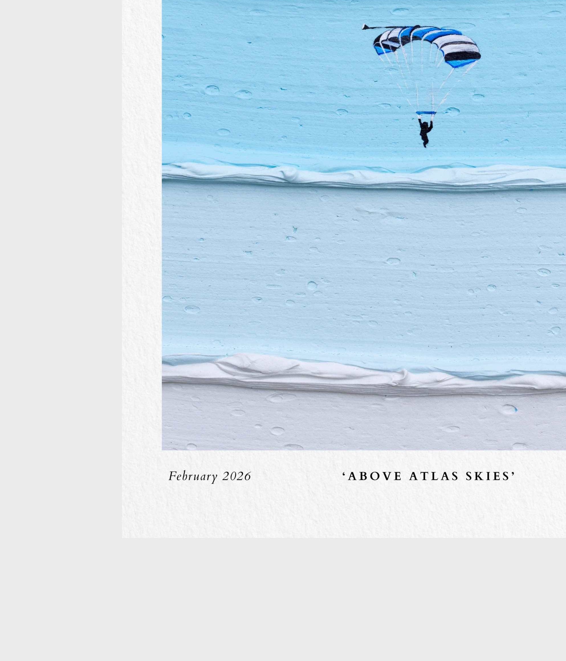 A square art print or poster featuring a minimalist photograph of a skydiver under a blue and white striped parachute over a light blue icy or snowy landscape. The print has a white border with the text 'February 2026' and '"ABOVE ATLAS SKIES"' printed at the bottom.