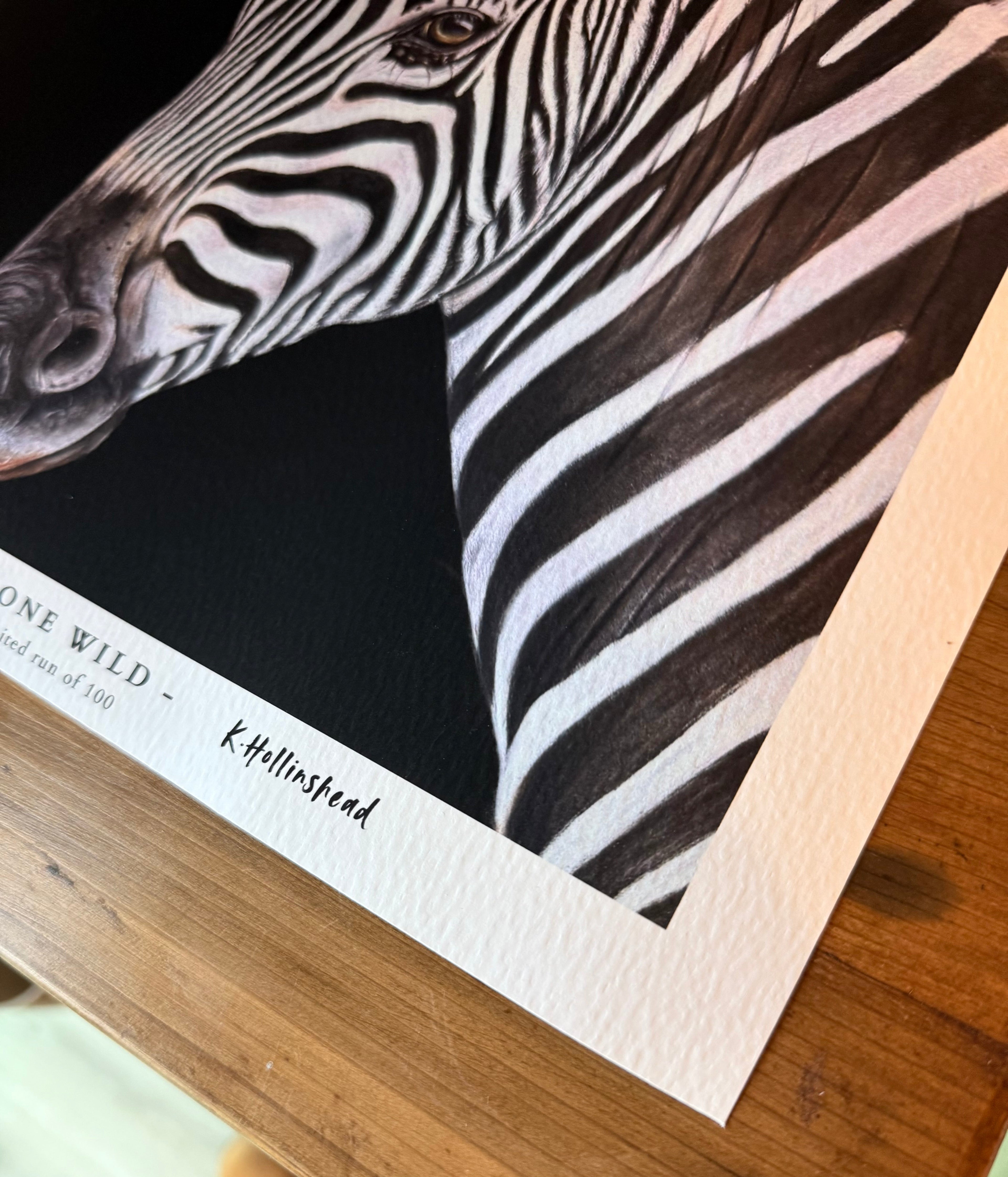 Close-up of a zebra print on a wooden surface with a signature visible.
