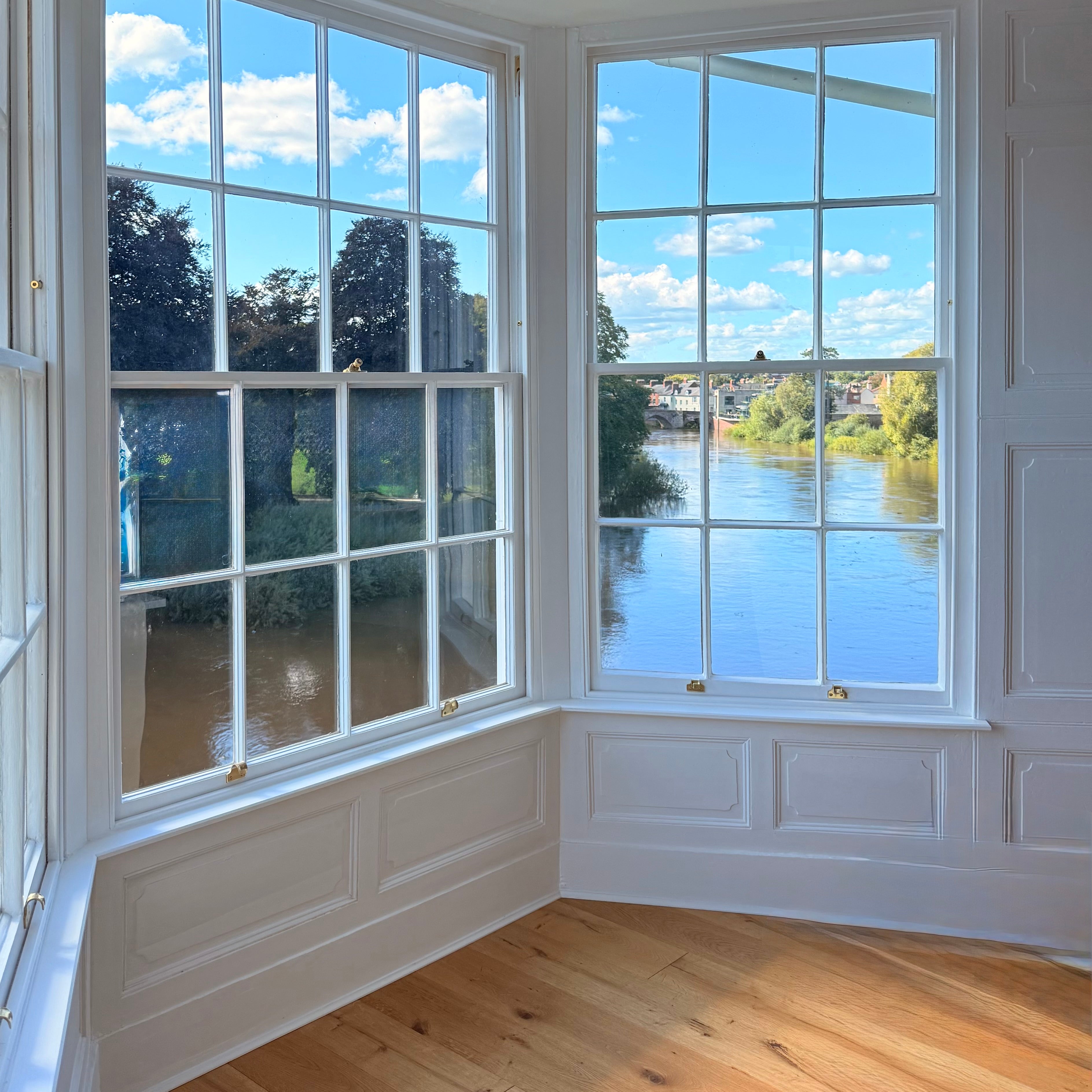 Room with large windows offering a view of trees and water.