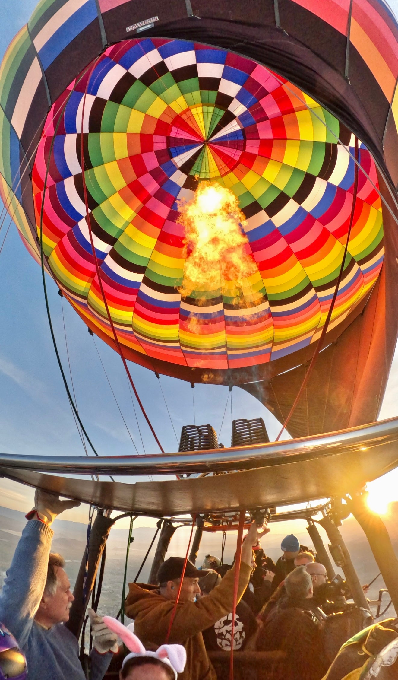 Colorful hot air balloon with people inside against a blue sky.