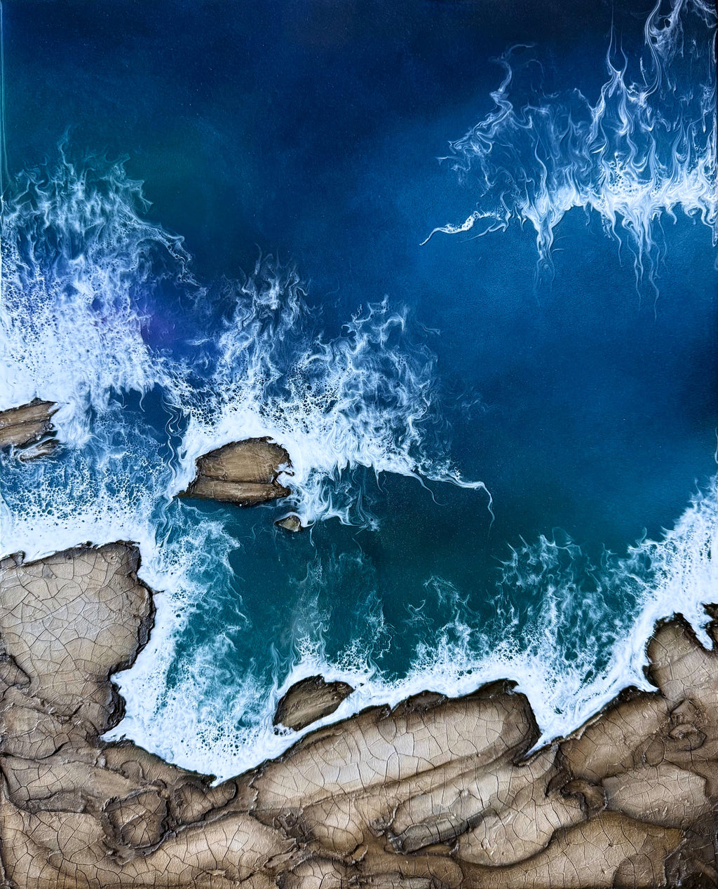 Aerial view of ocean waves crashing against a rocky coastline.
